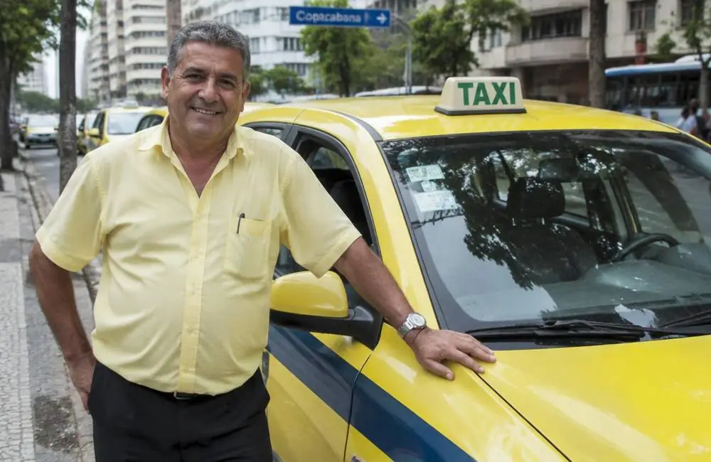 Taxista ao lado do seu táxi amarelo